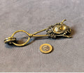 Brass Skirt Lifter — Brass, late 19th century